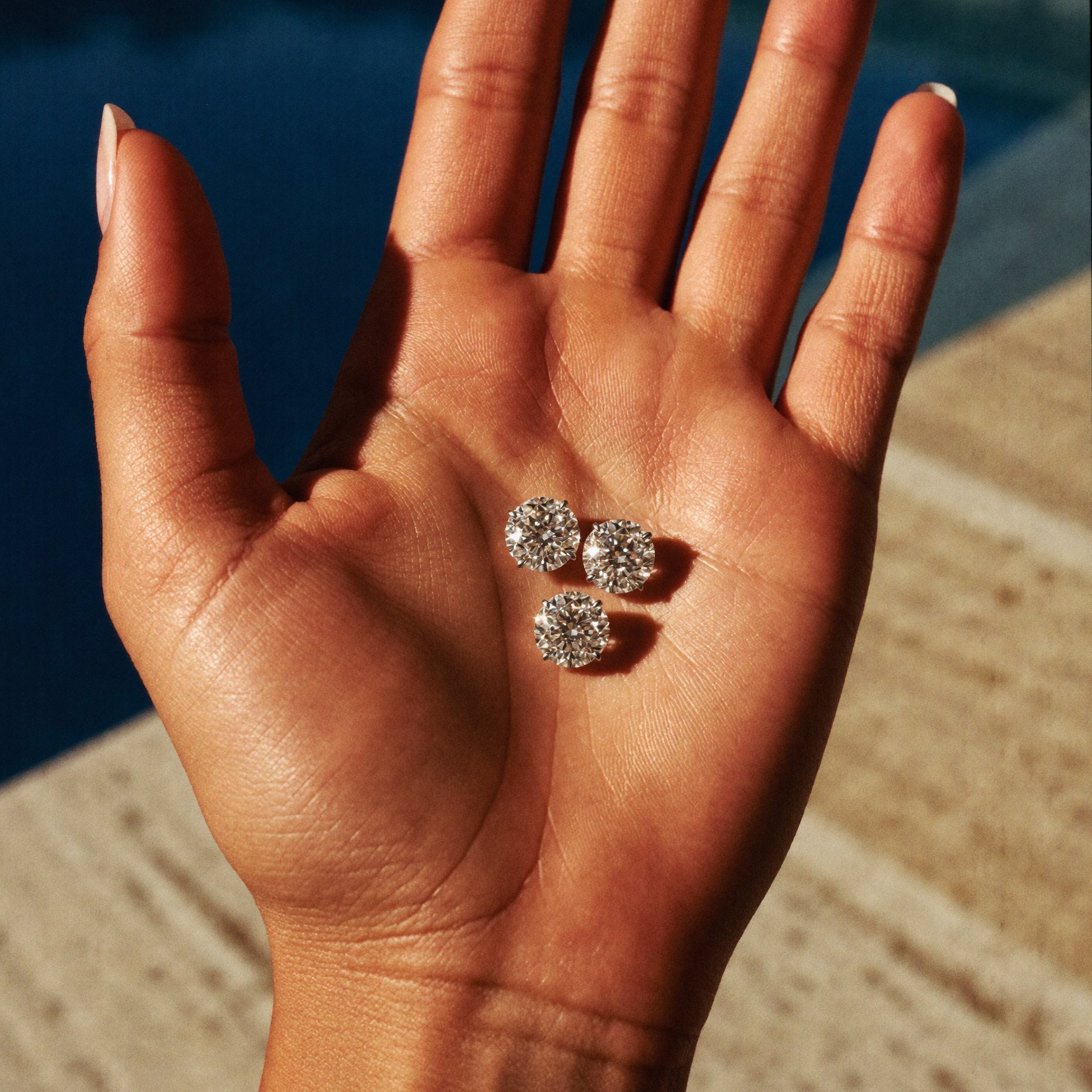 Loose round brilliant diamonds resting in an open palm in bright sun