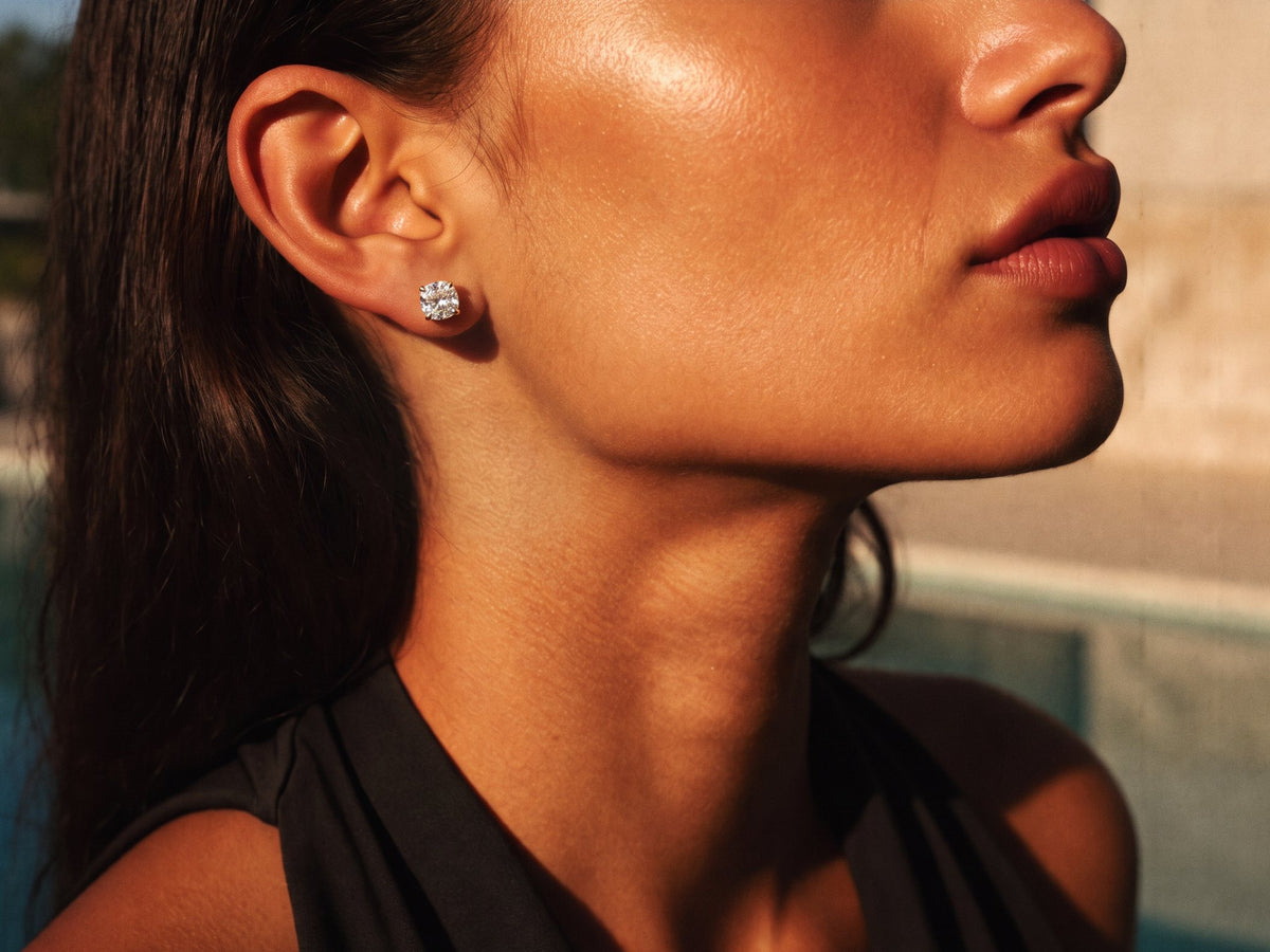 Profile close-up of an ear wearing a gold round diamond solitaire stud earring